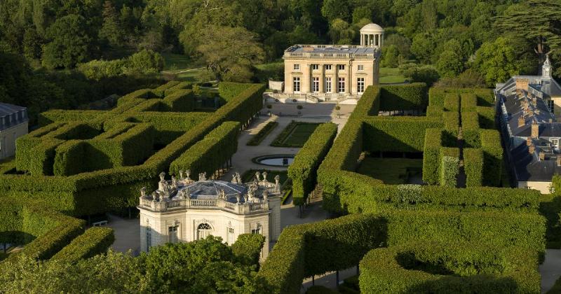Une vue majestueuse du Château de Versailles sous un ciel bleu, mettant en valeur son architecture classique et ses toits dorés, un symbole de la grandeur française.